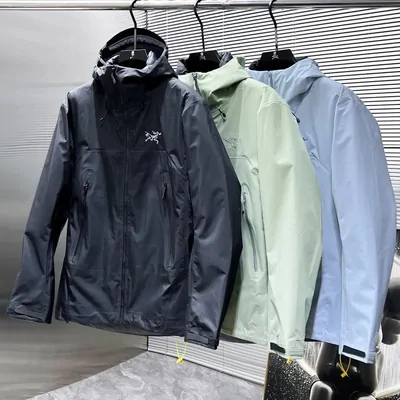 Three hooded shell jackets in navy, mint and pale blue hanging on a rail